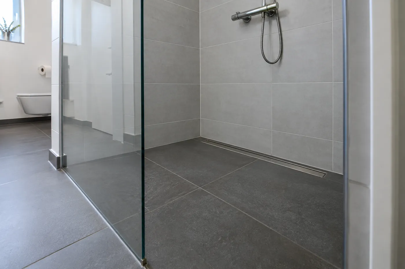 Bodengleich geflieste Dusche mit Duschrinne und Glaswand